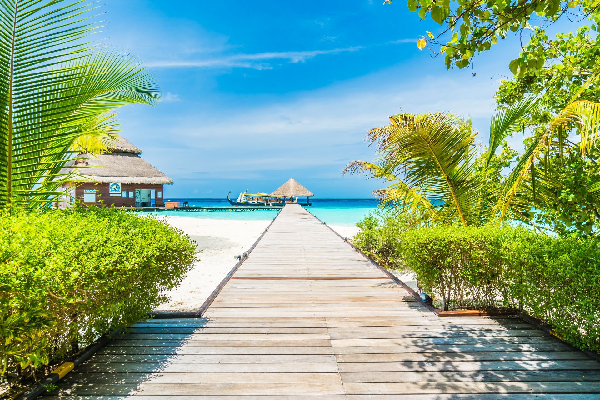 A wooden walkway leading to a tropical beach.