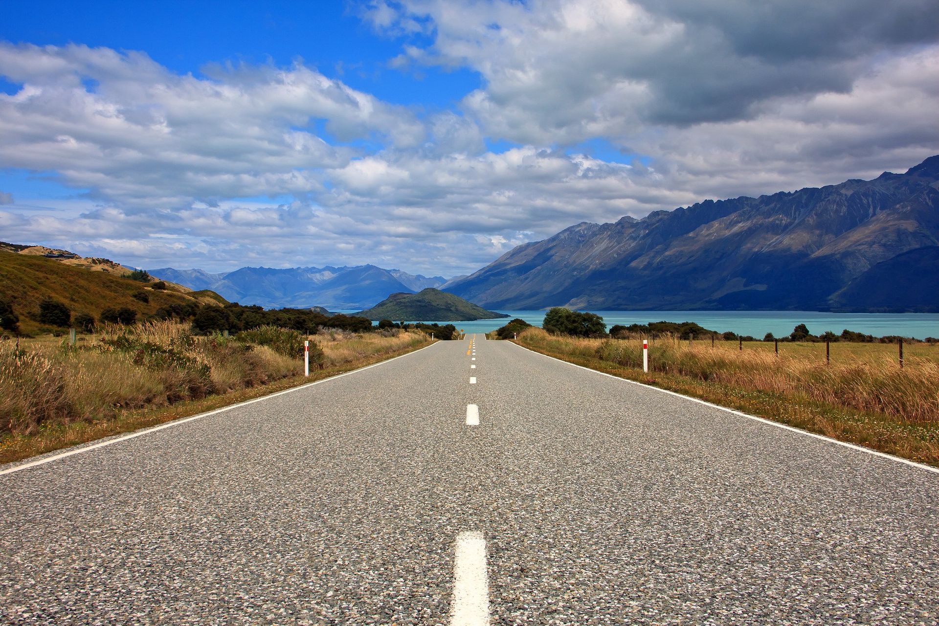 An empty road with mountains and a lake in the background