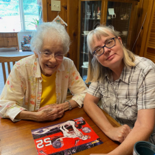 Two women are sitting at a table with a picture of a race car on it.