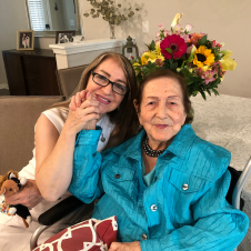 A woman is sitting next to an older woman in a wheelchair.