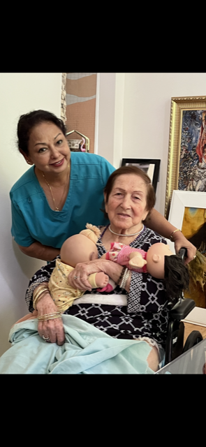 A woman in a wheelchair is holding a baby and a nurse is standing next to her.
