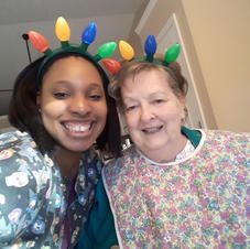 Two women are posing for a picture together while wearing christmas lights on their heads.