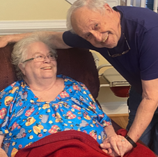 A man standing next to an elderly woman in a chair