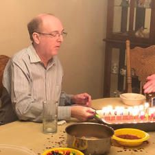 A man is sitting at a table with a cake and candles.