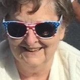 A close up of a woman wearing sunglasses and smiling.