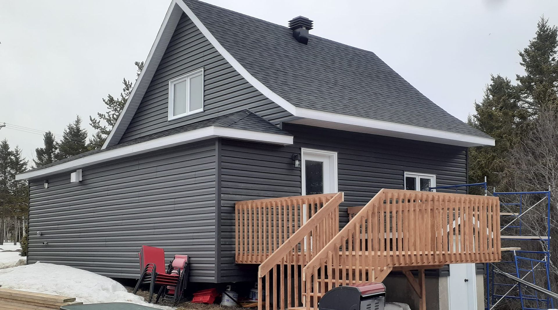 Une petite maison avec une terrasse en bois et des escaliers.