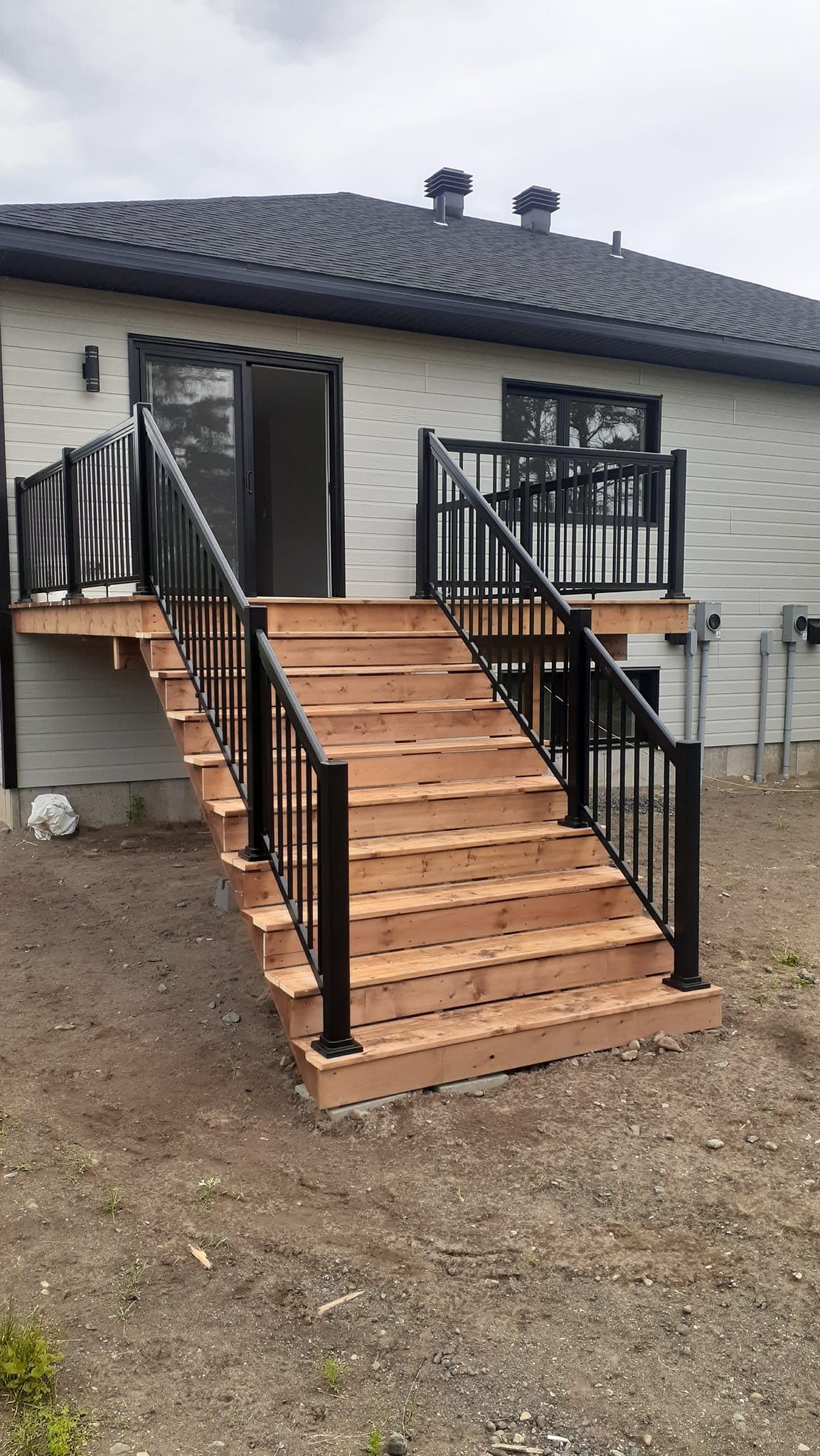Une terrasse en bois avec des escaliers menant à une maison.