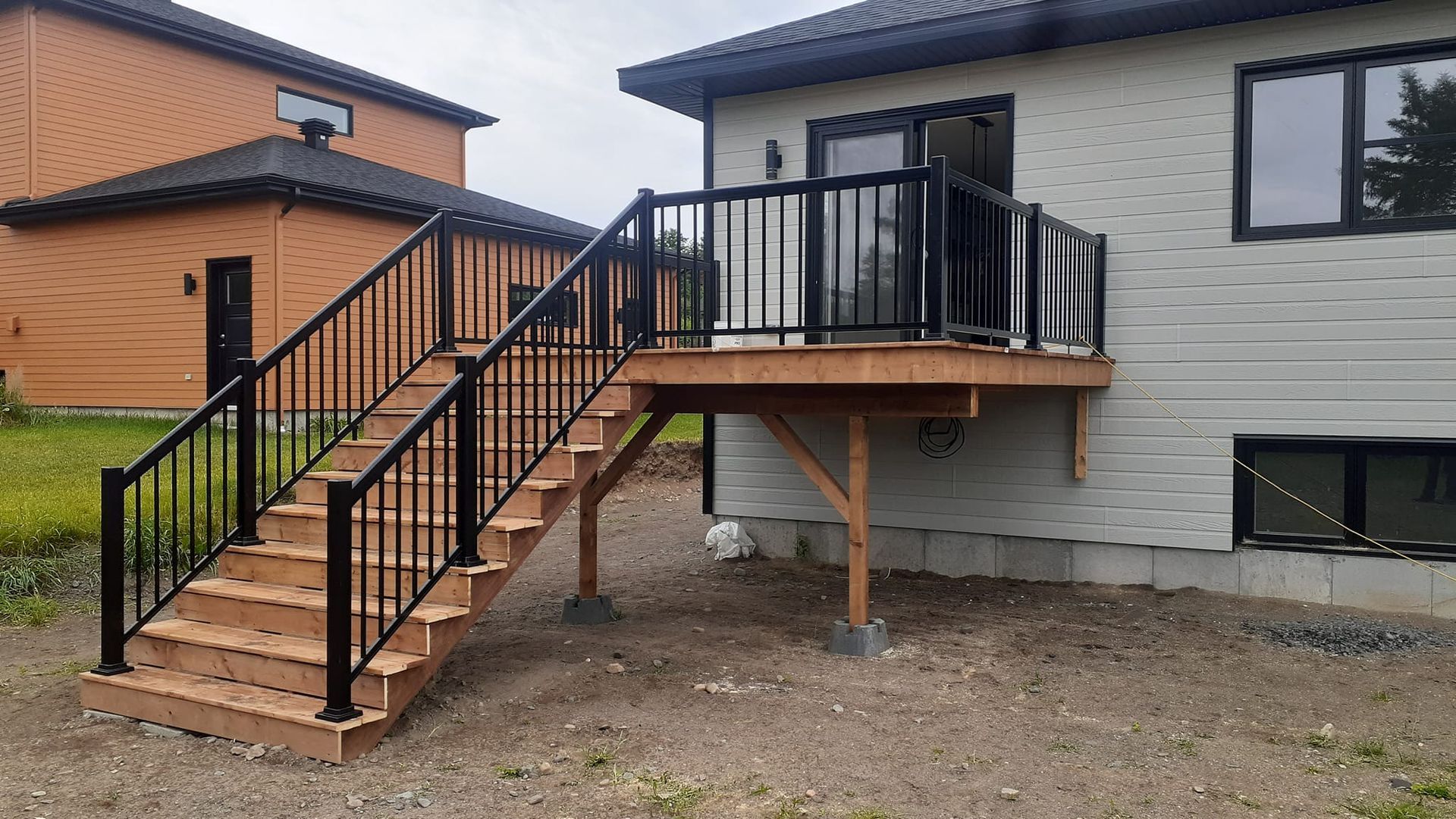 Une terrasse en bois avec des escaliers qui y mènent se trouve devant une maison.
