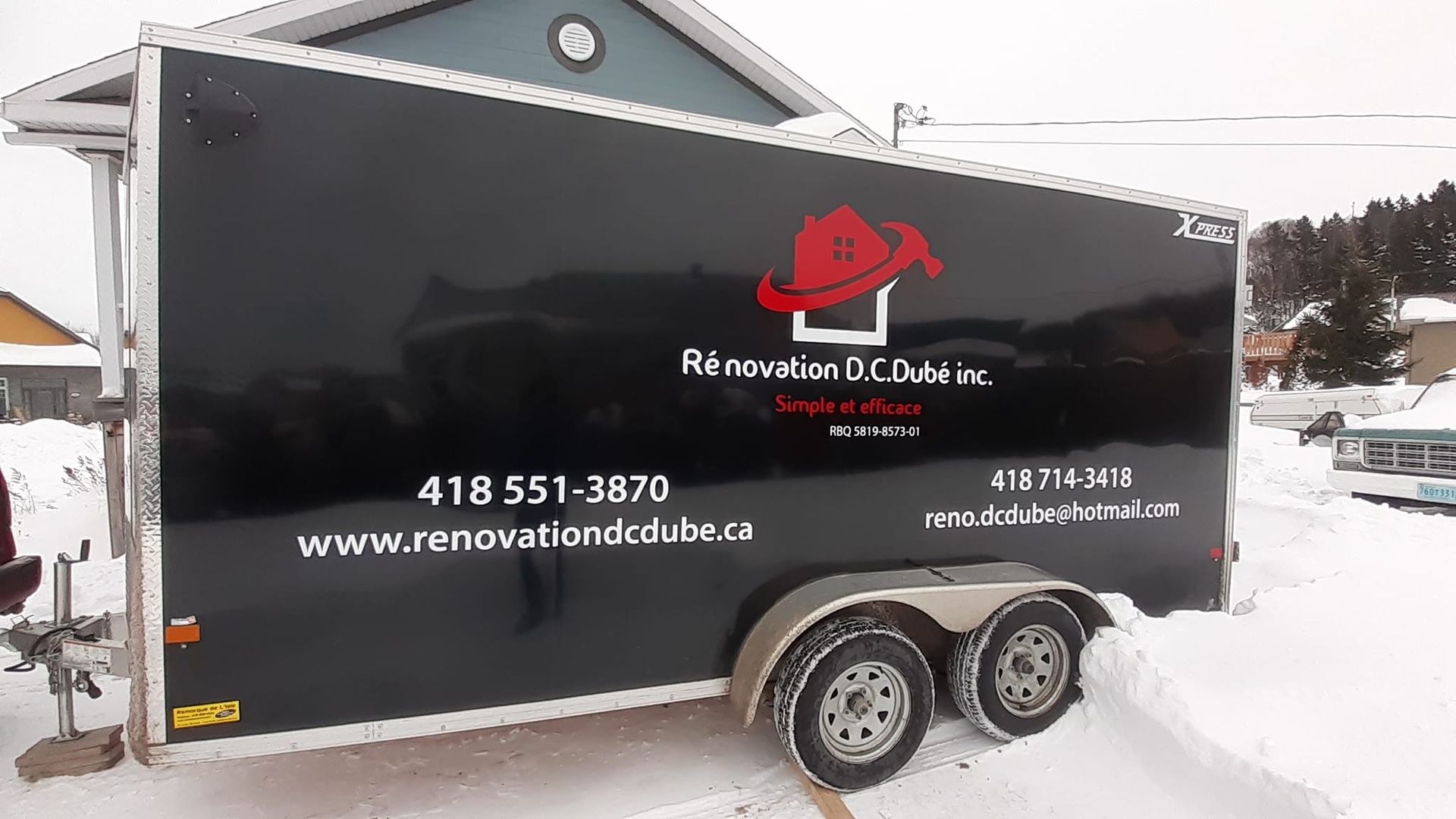 Une remorque noire avec un chapeau rouge dessus est garée dans la neige.