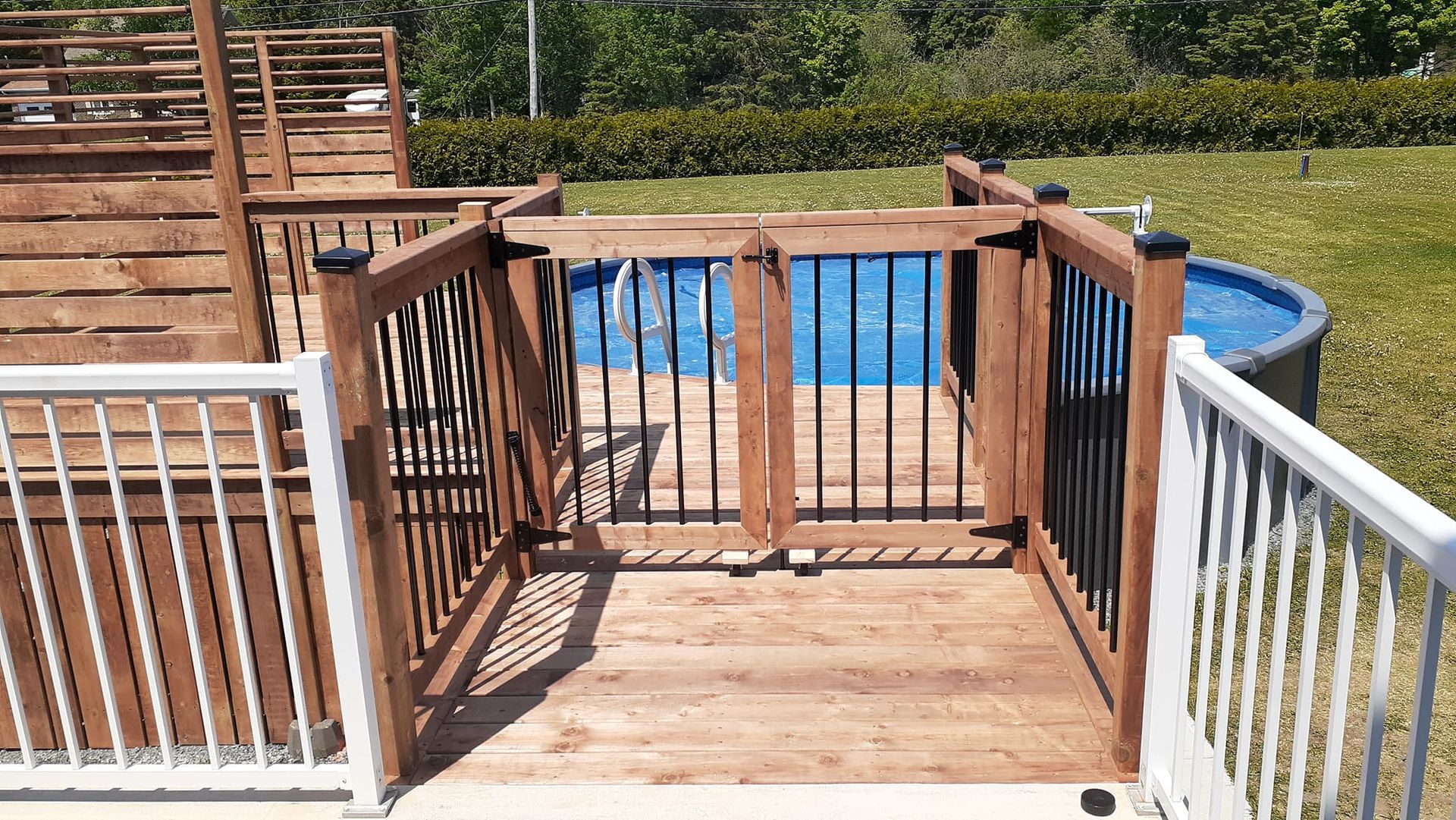 Une terrasse en bois avec un portail menant à une piscine.