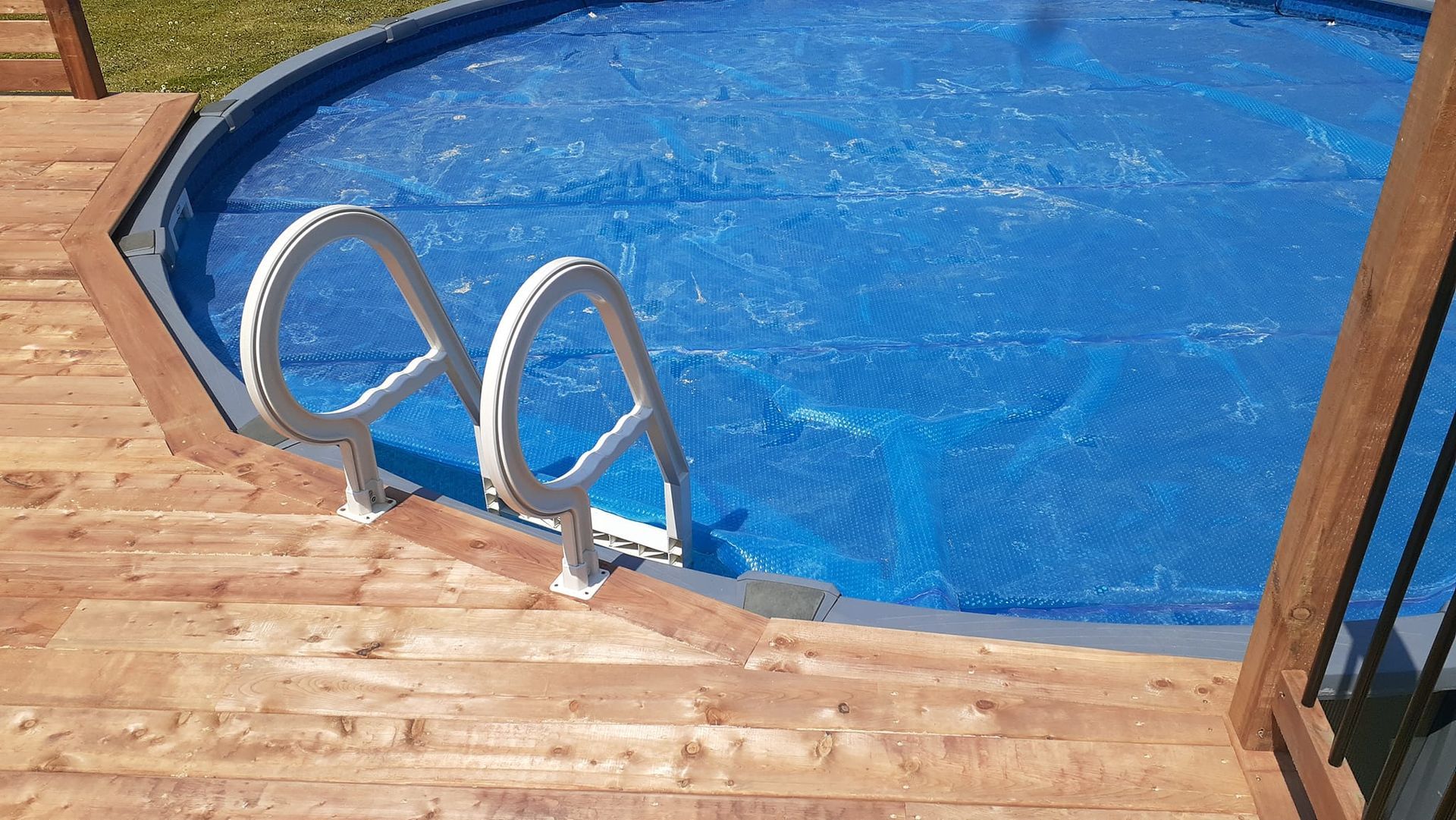 Une piscine avec une terrasse en bois et des escaliers qui y mènent.