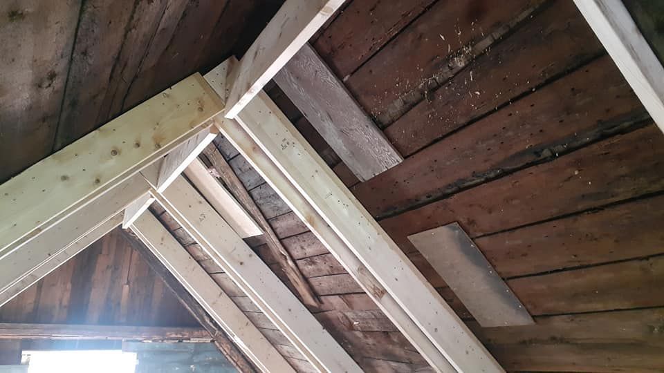 Le plafond d'un grenier avec des poutres en bois et une fenêtre.