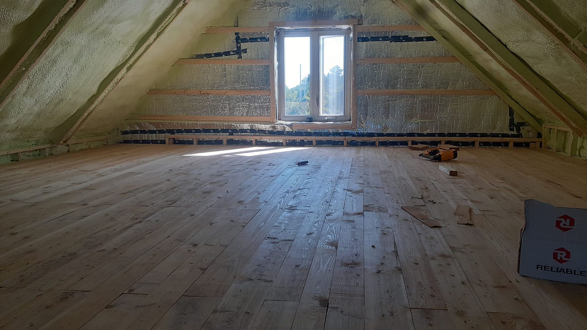 Un grenier vide avec un plancher en bois et une fenêtre.