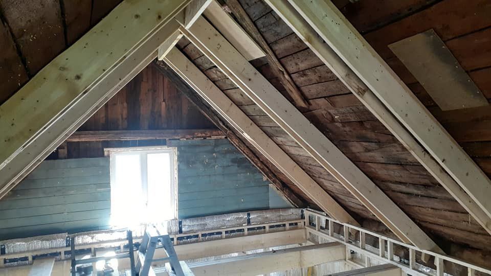 Un toit en bois avec une fenêtre et une échelle dans le grenier.