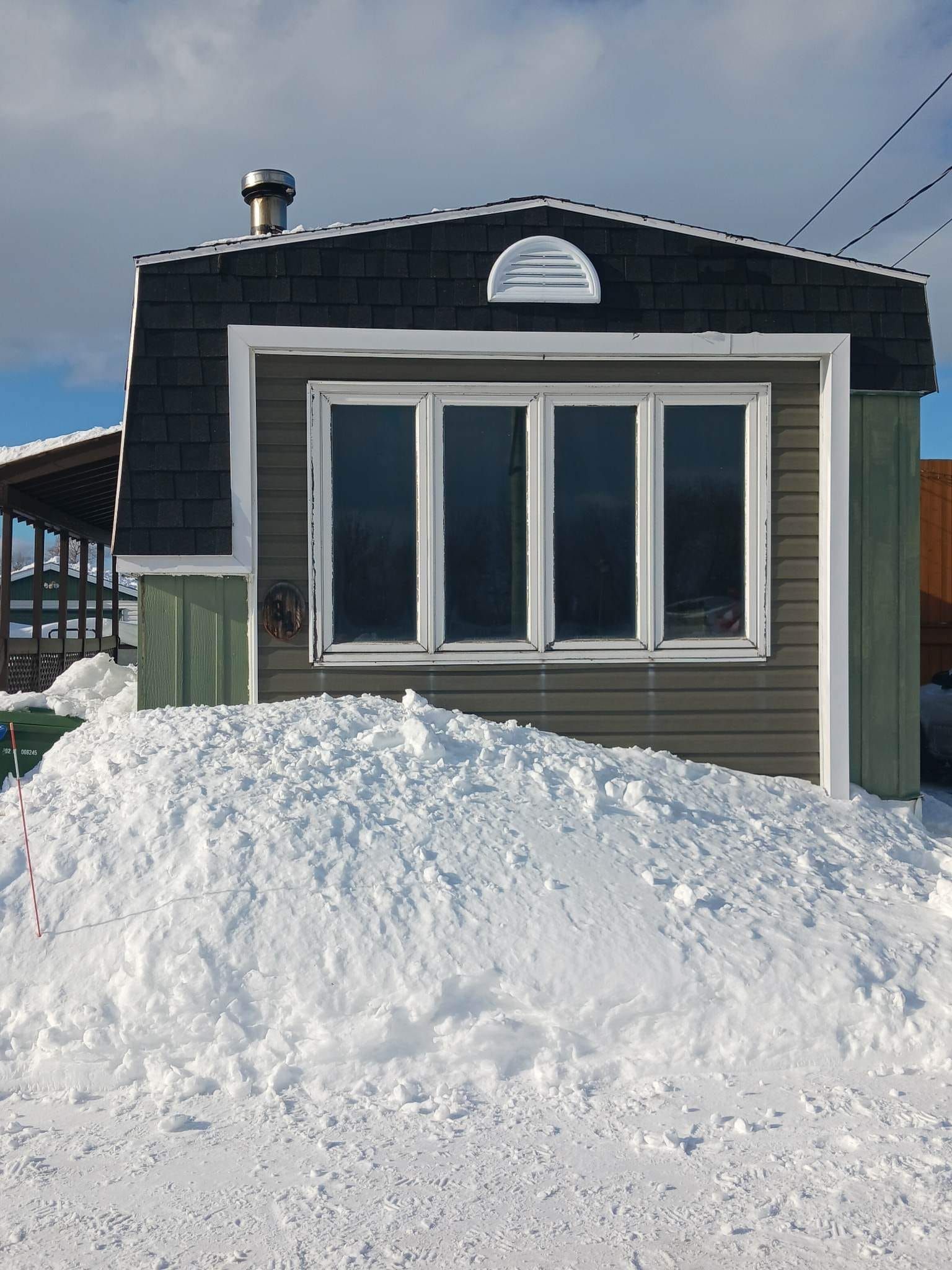 Une maison avec un gros tas de neige devant elle