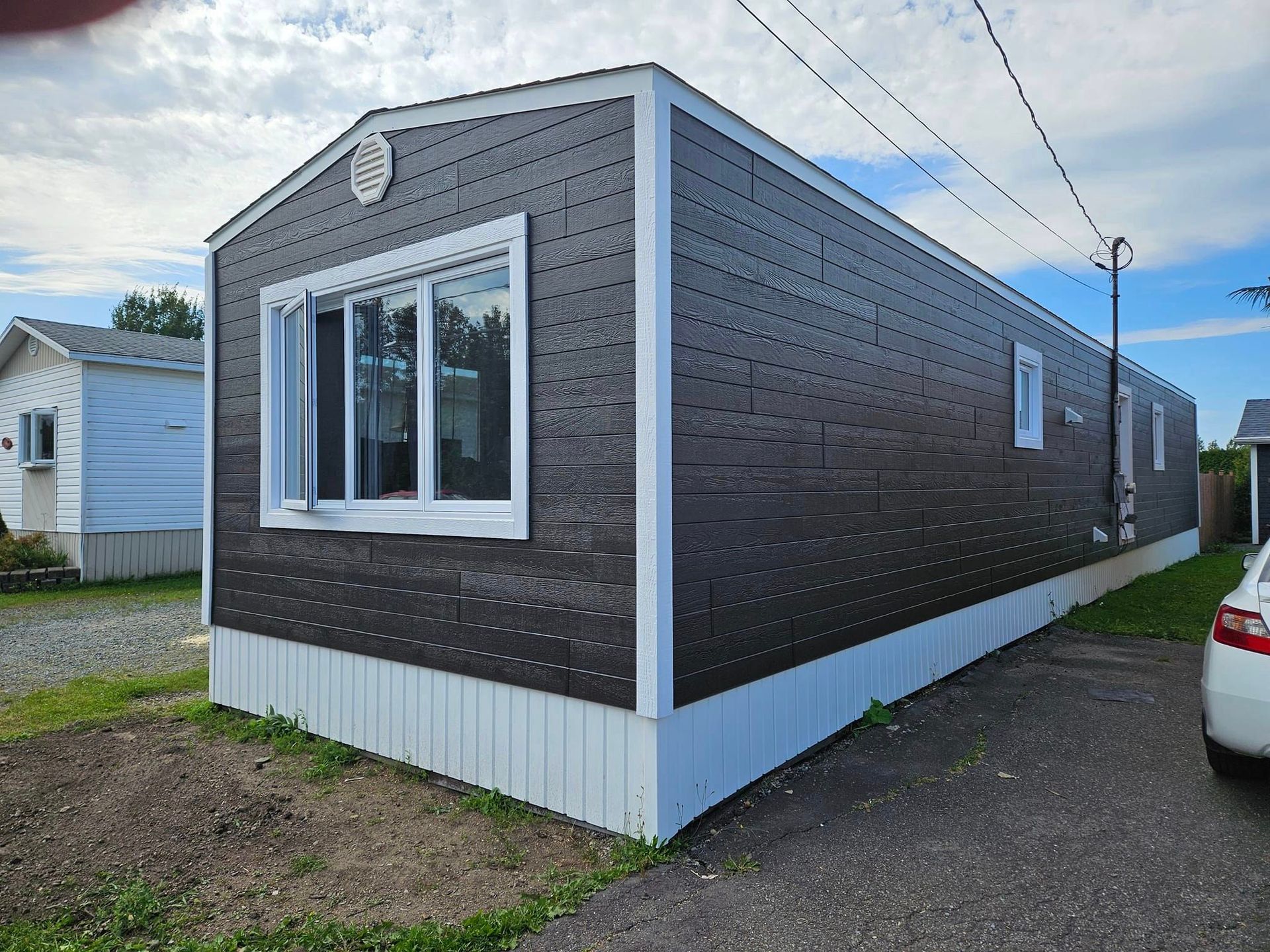 Un mobil home avec une voiture garée devant.