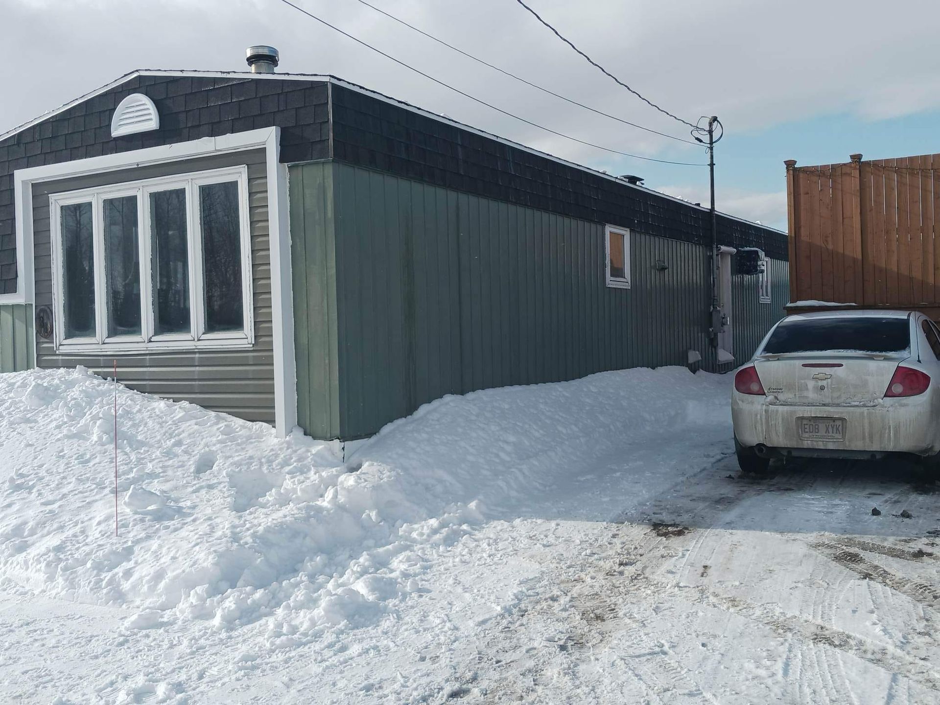 Une voiture est garée devant une maison sous la neige.