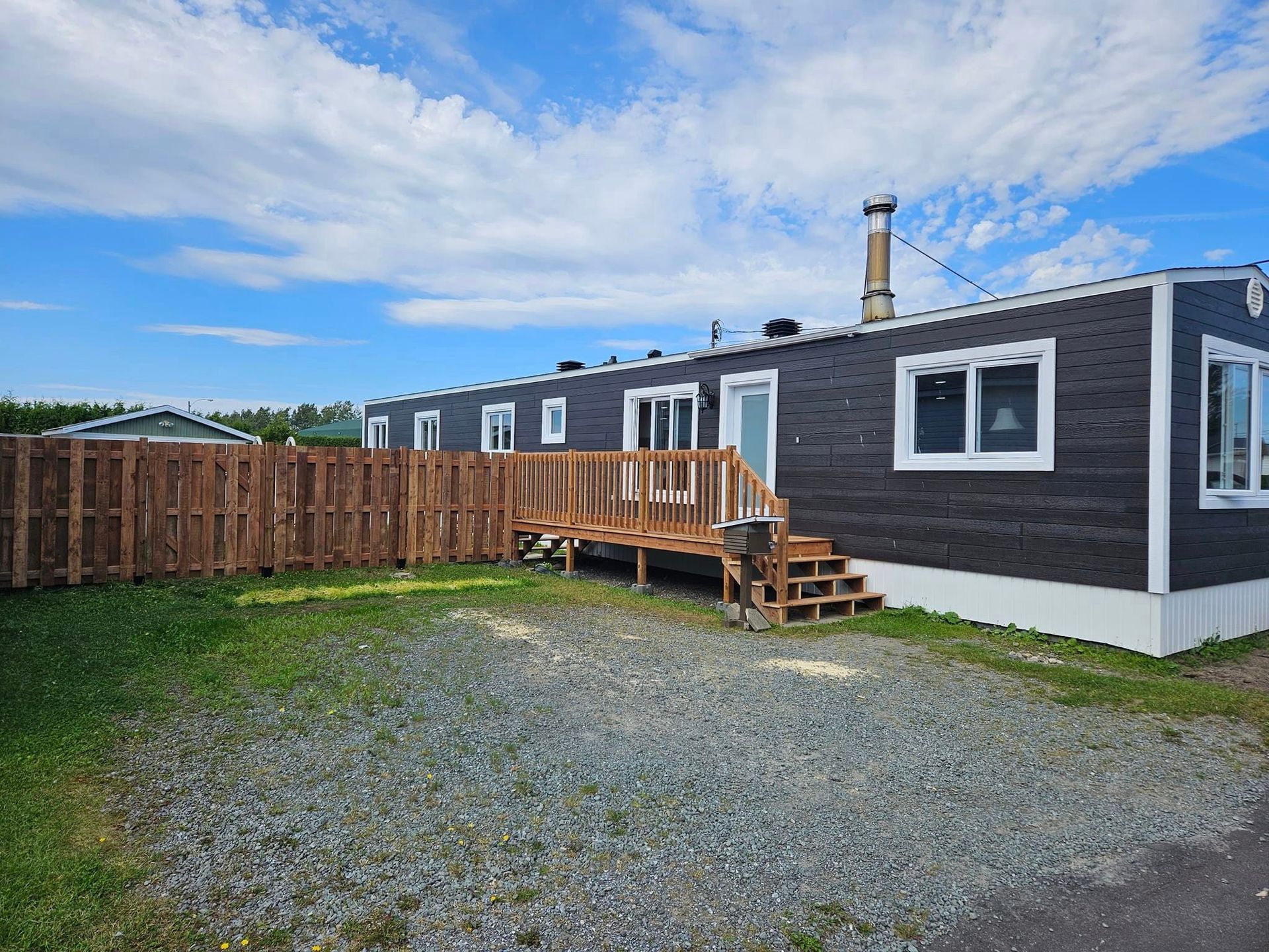 Un mobil home avec une clôture en bois devant.