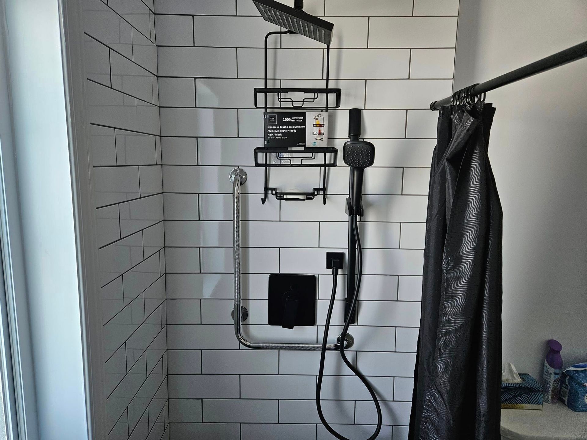 Une salle de bain avec du carrelage blanc et un rideau de douche noir