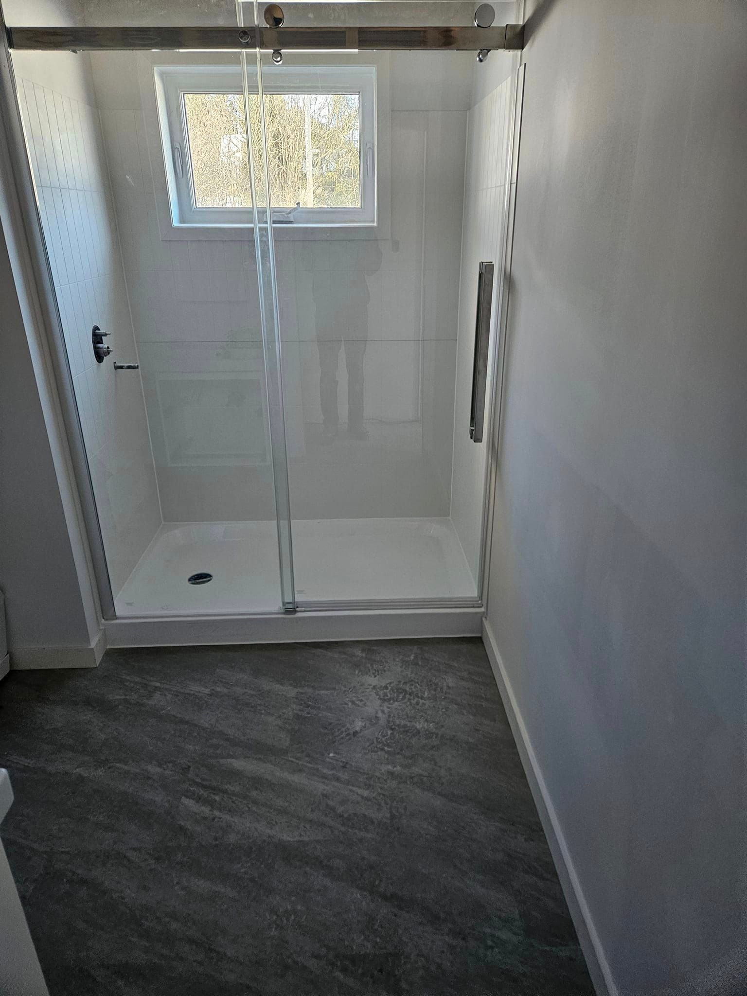 Une salle de bain avec une porte de douche coulissante en verre et une fenêtre.