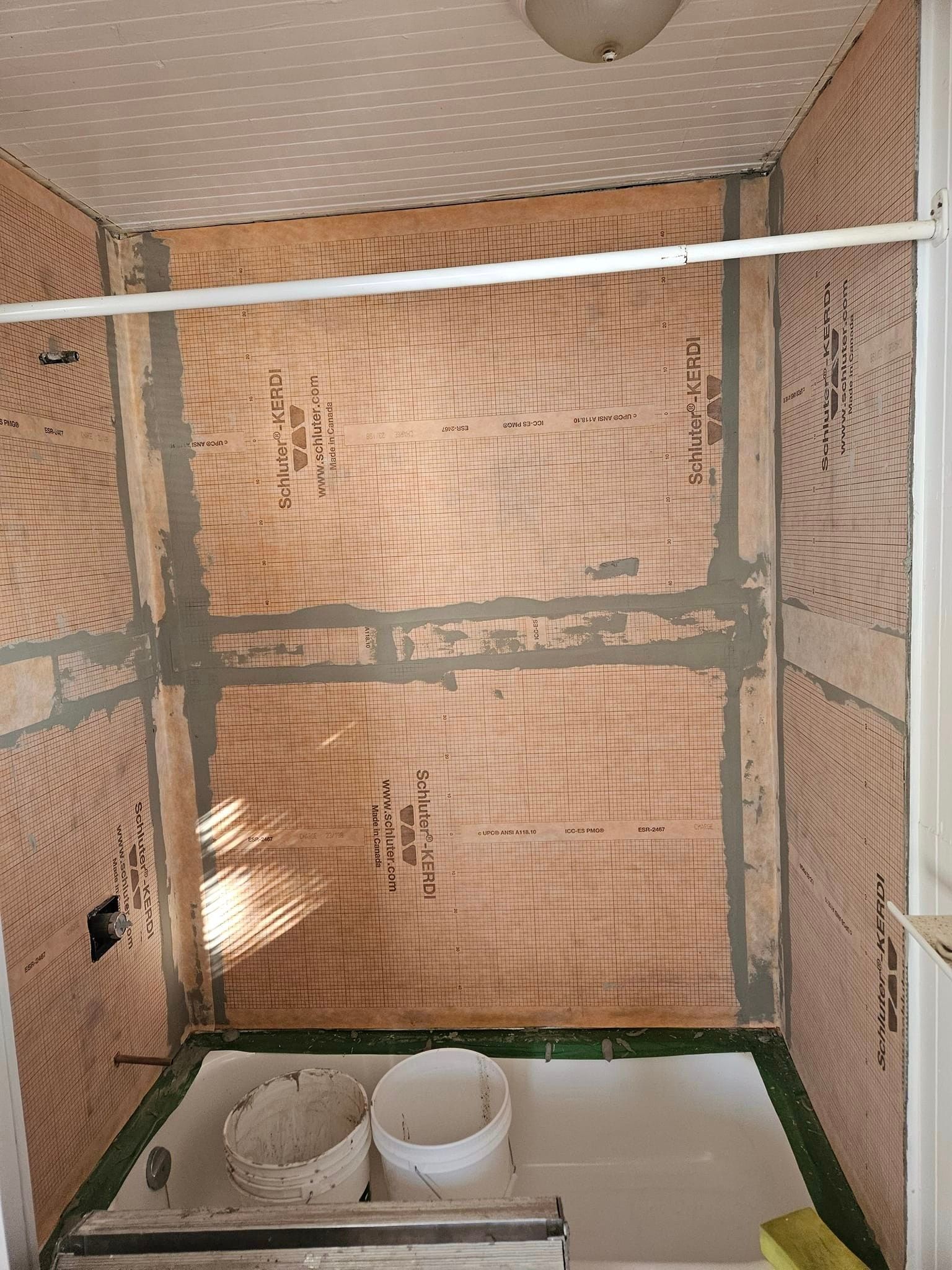 Une salle de bain avec un rideau de douche et un seau sur le sol.