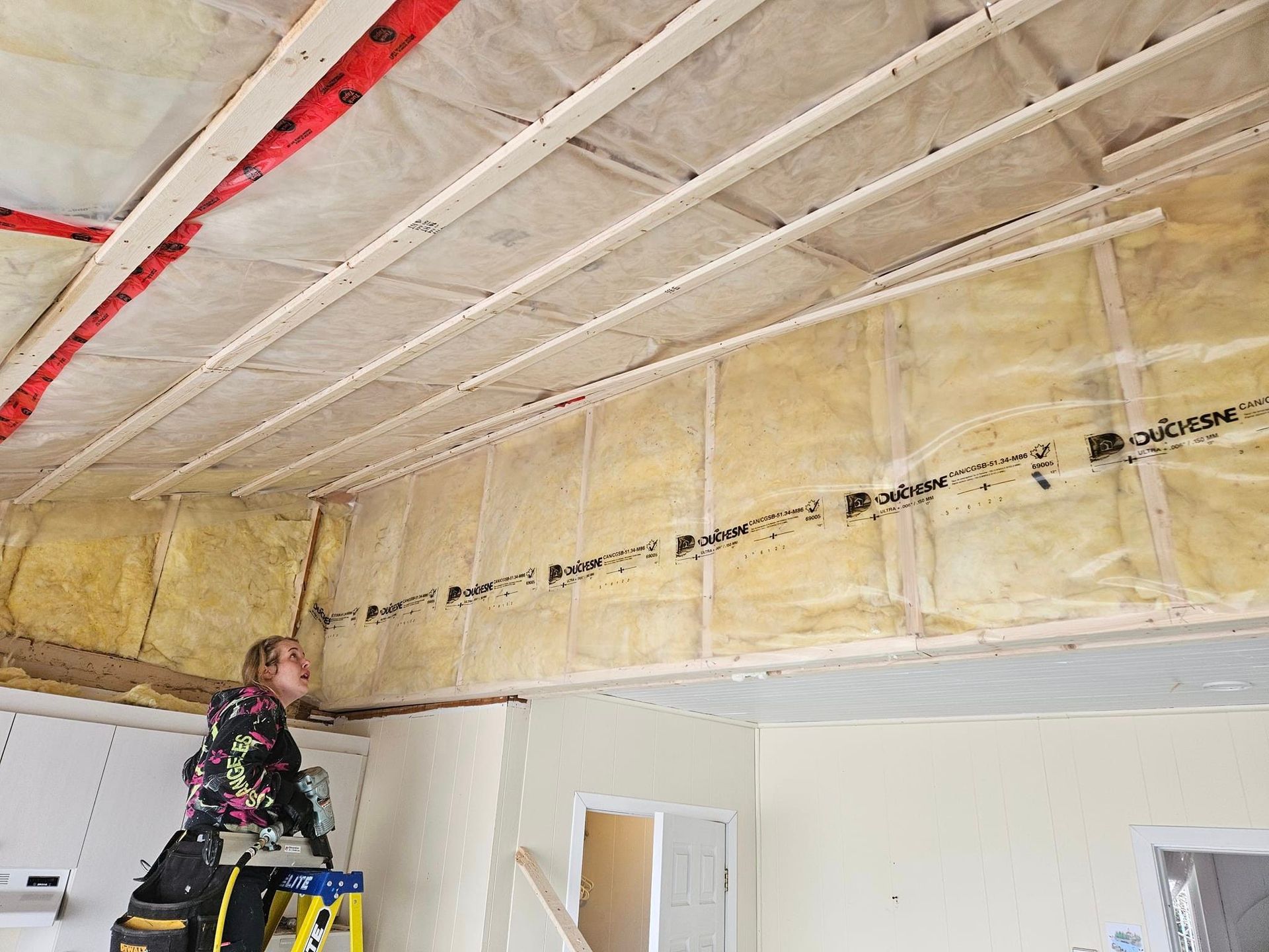 Une femme se tient debout sur une échelle dans une pièce.