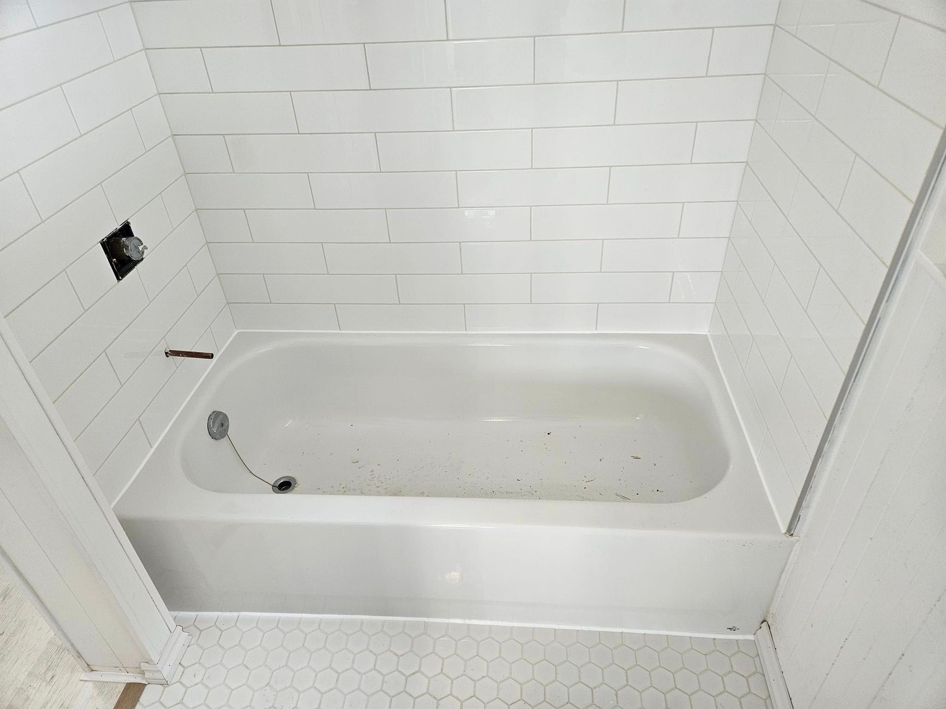 Une baignoire vide dans une salle de bain avec du carrelage blanc