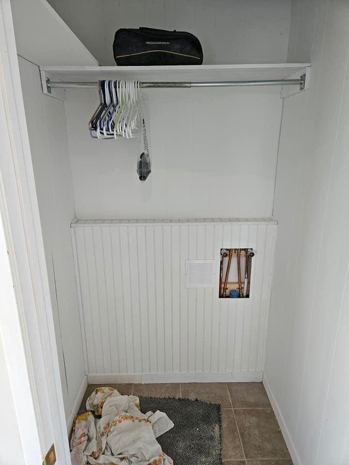 Un petit placard avec une valise sur une étagère.