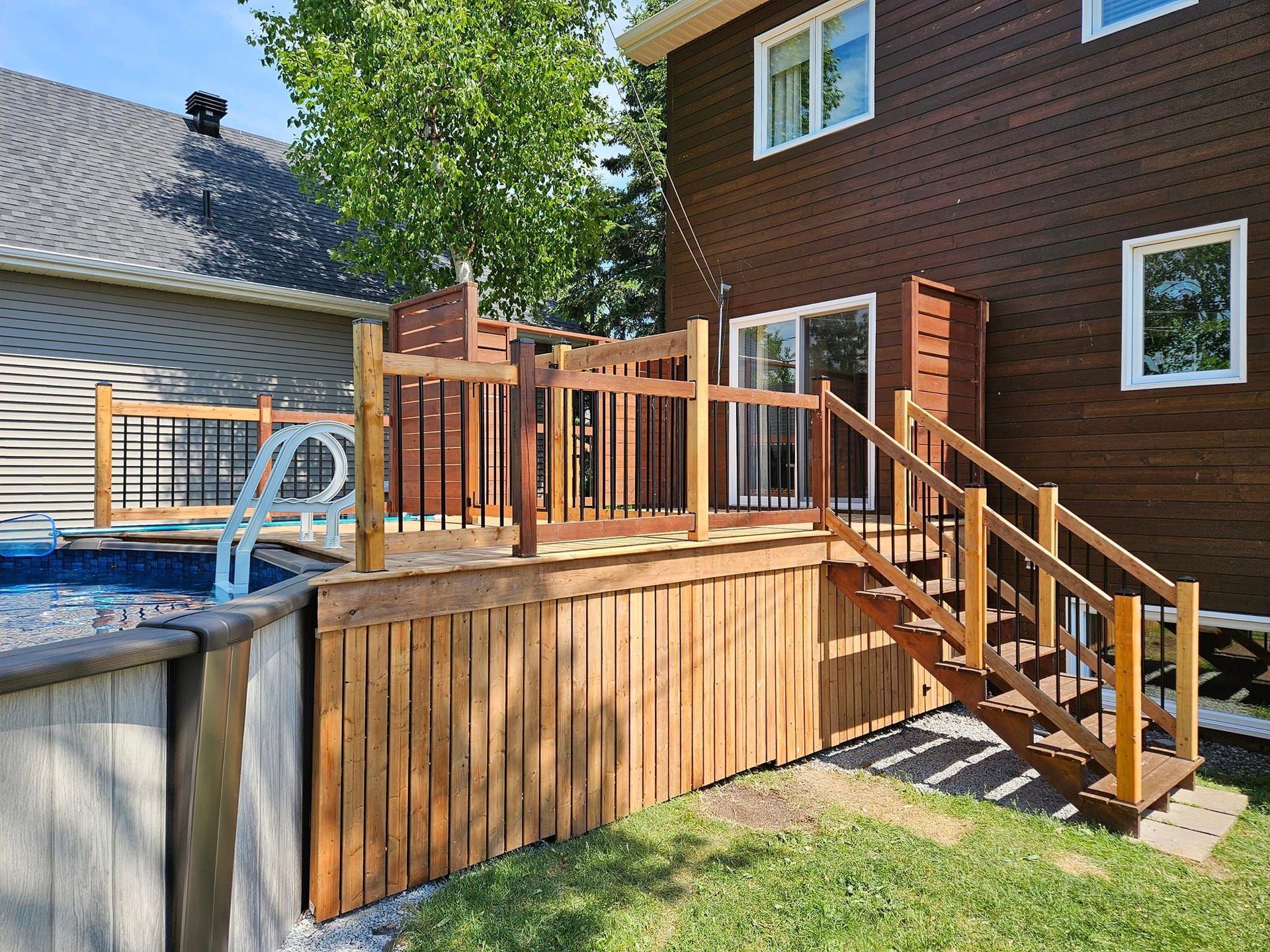 Une terrasse en bois avec des escaliers menant à côté d'une piscine.