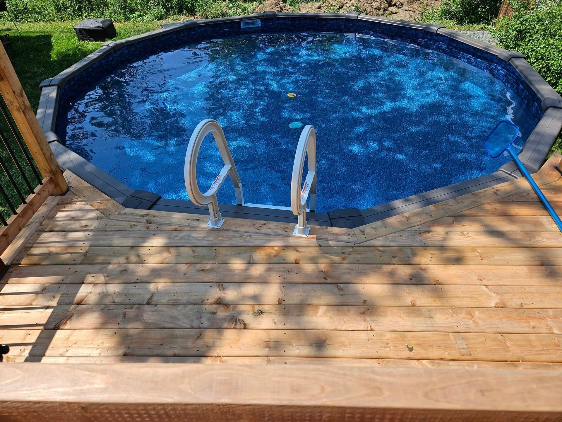 Une piscine est posée sur une terrasse en bois.