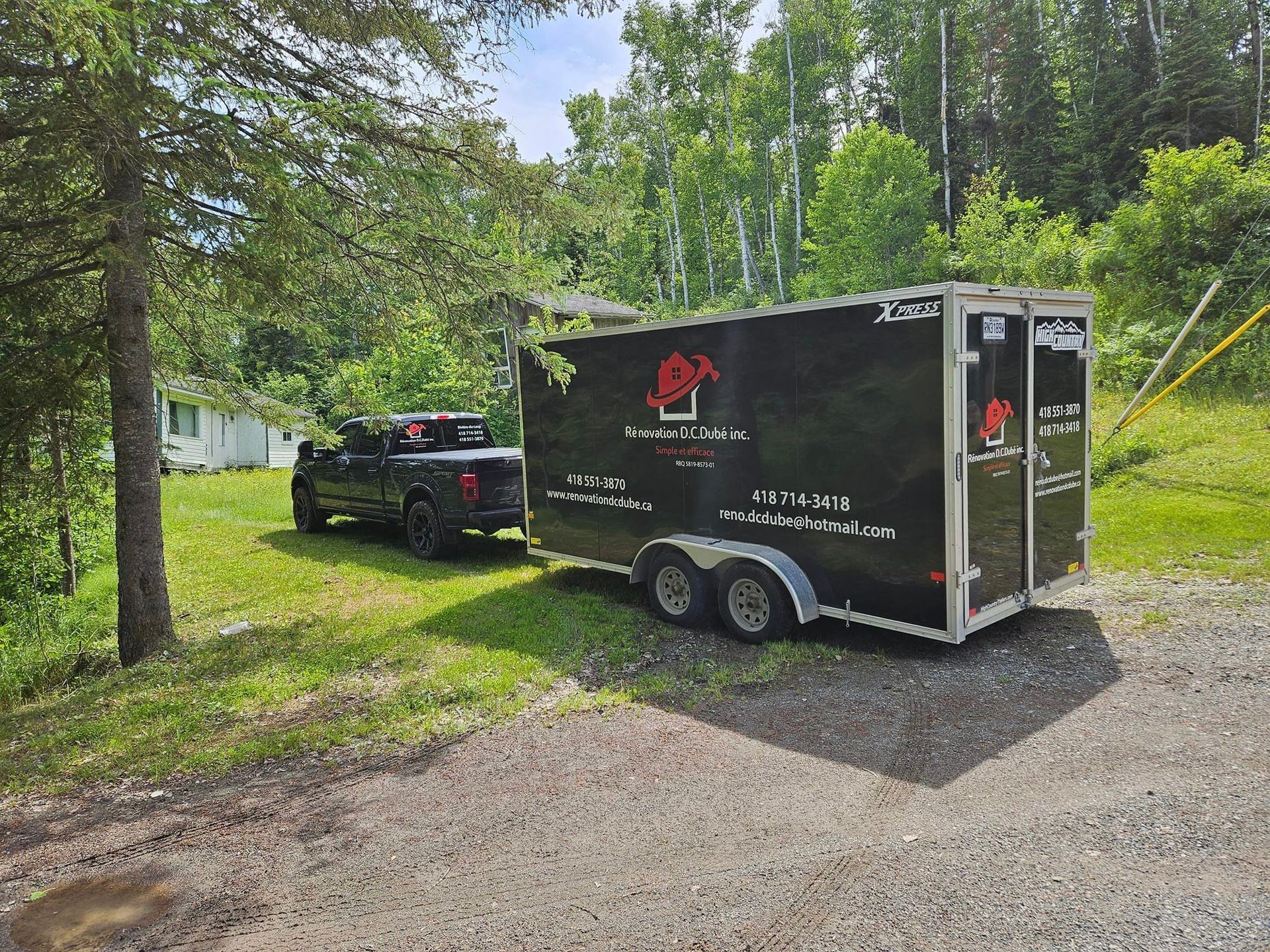 Un camion noir est garé à côté d'une remorque noire.