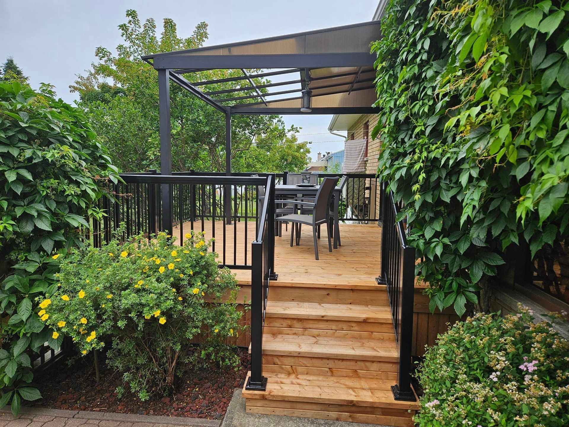 Une terrasse en bois avec des escaliers qui y mènent et une pergola.