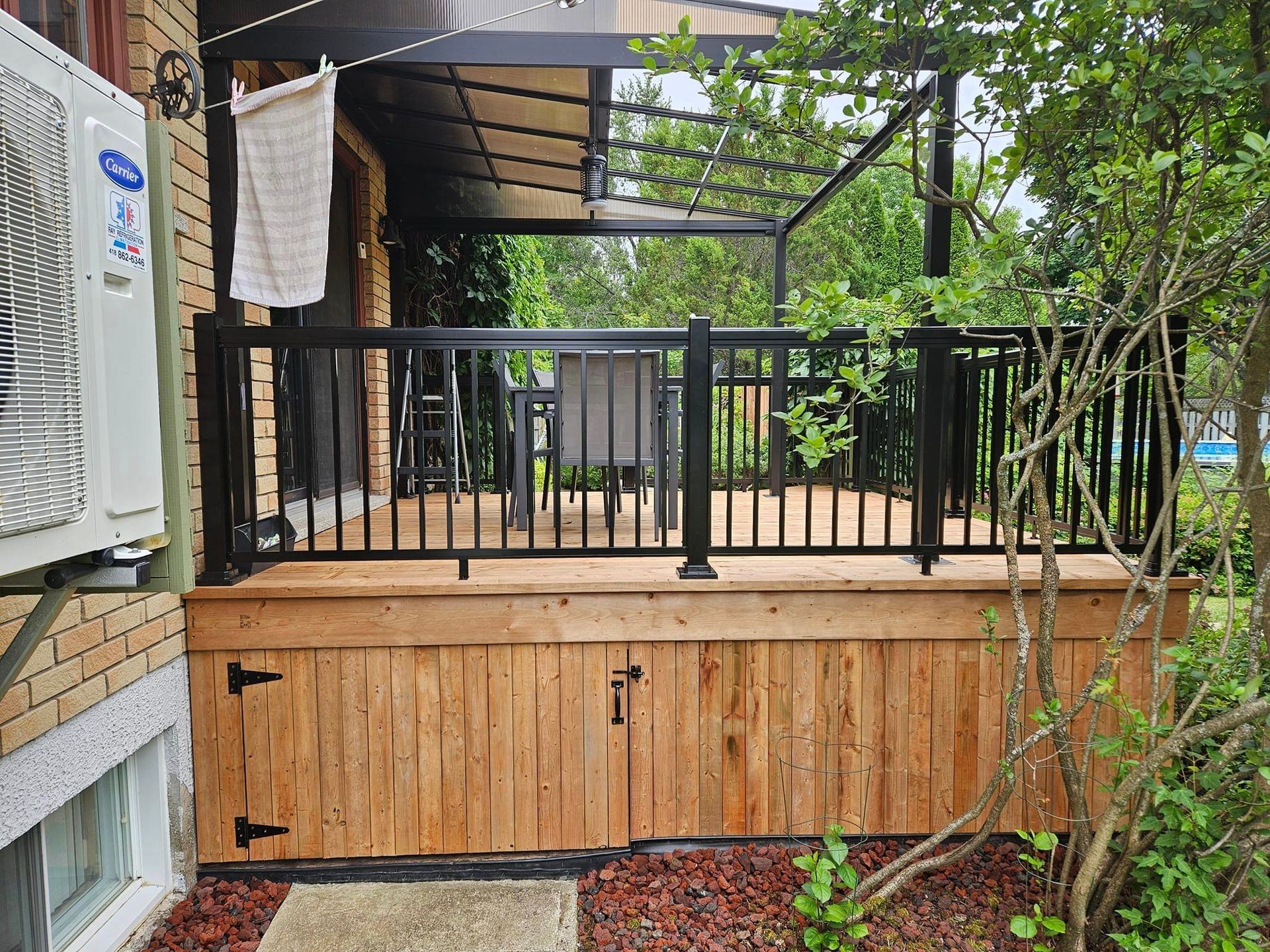Une terrasse en bois avec une balustrade noire et une porte noire.