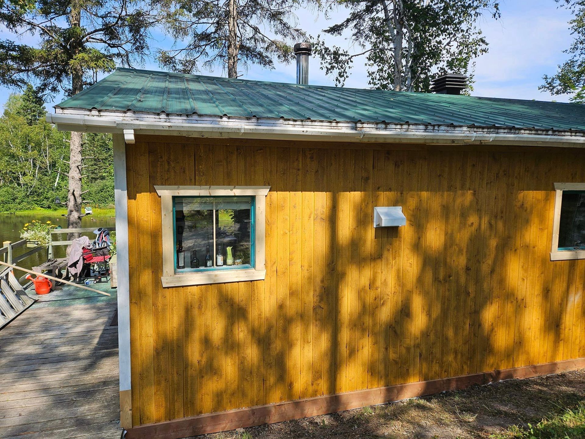 Une petite maison jaune avec un toit vert et deux fenêtres.