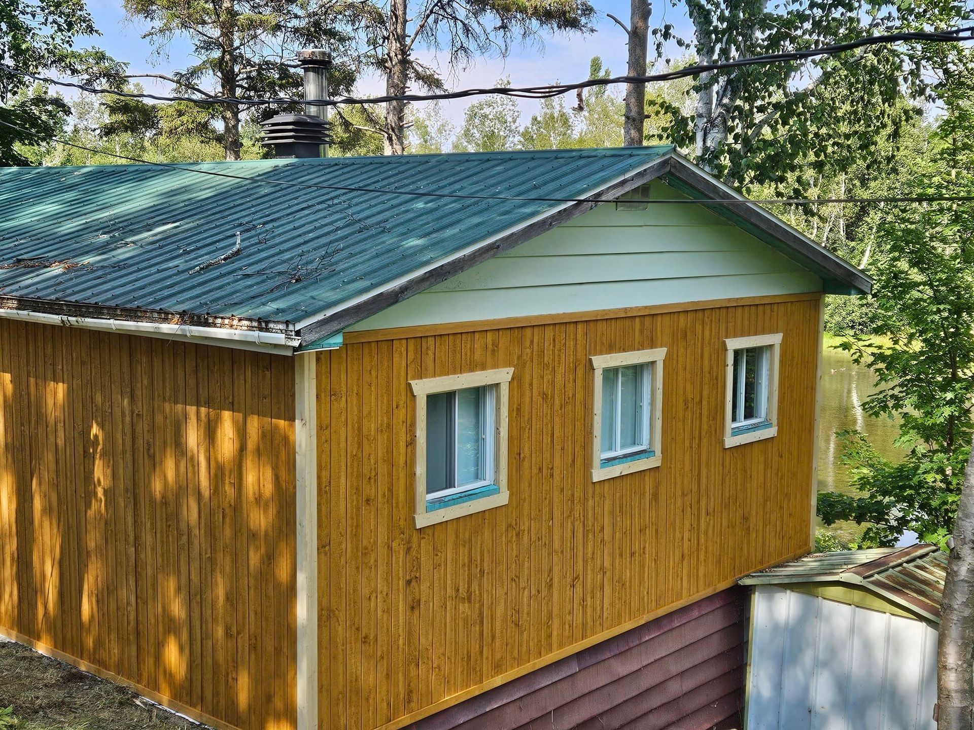 Une petite maison en bois avec un toit vert et des fenêtres