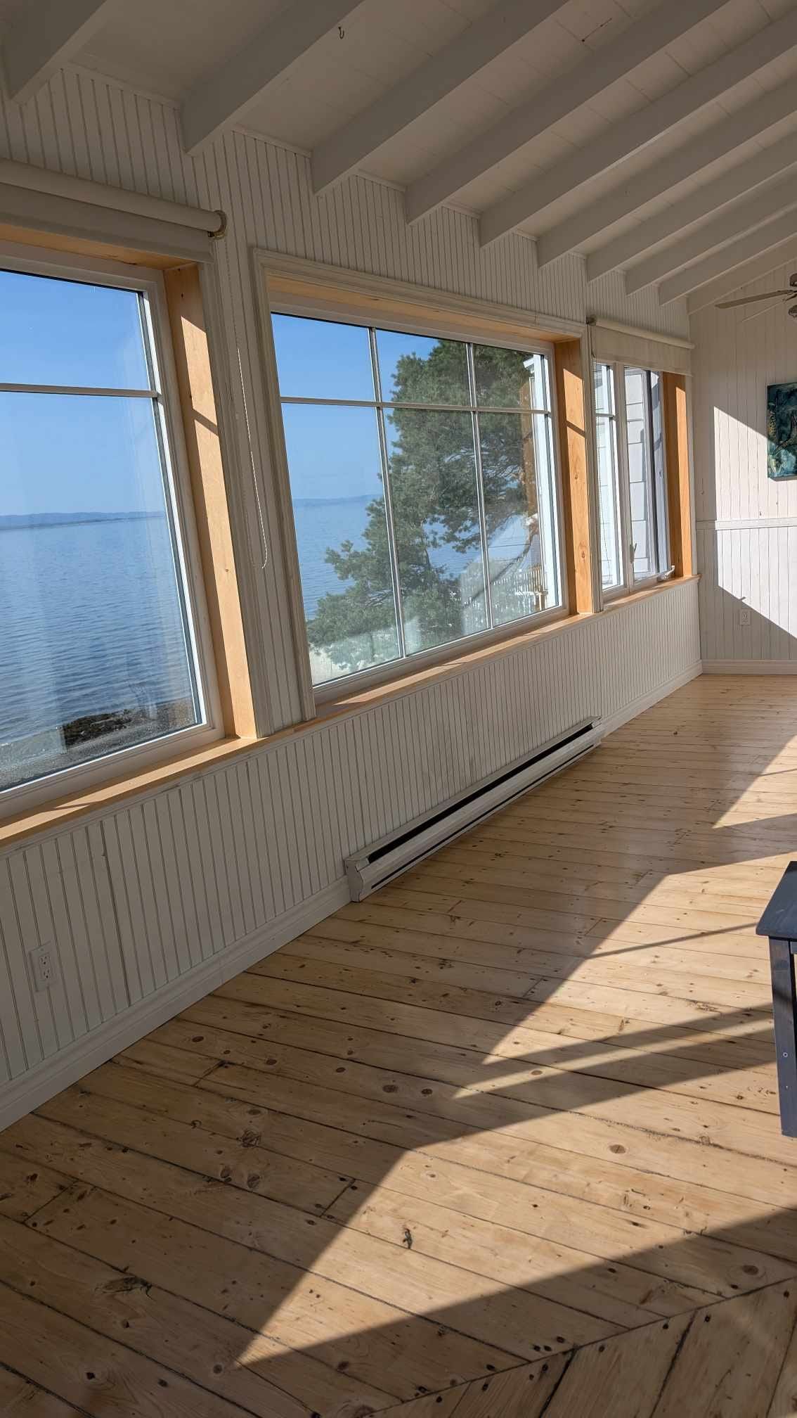 Une grande pièce avec beaucoup de fenêtres et un plancher en bois.