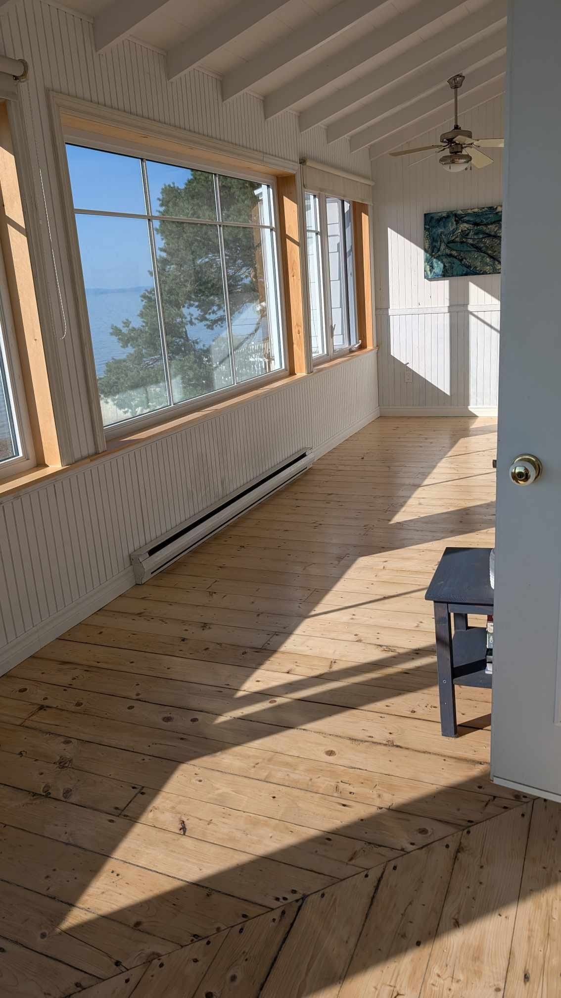 Une pièce avec beaucoup de fenêtres et un plancher en bois.