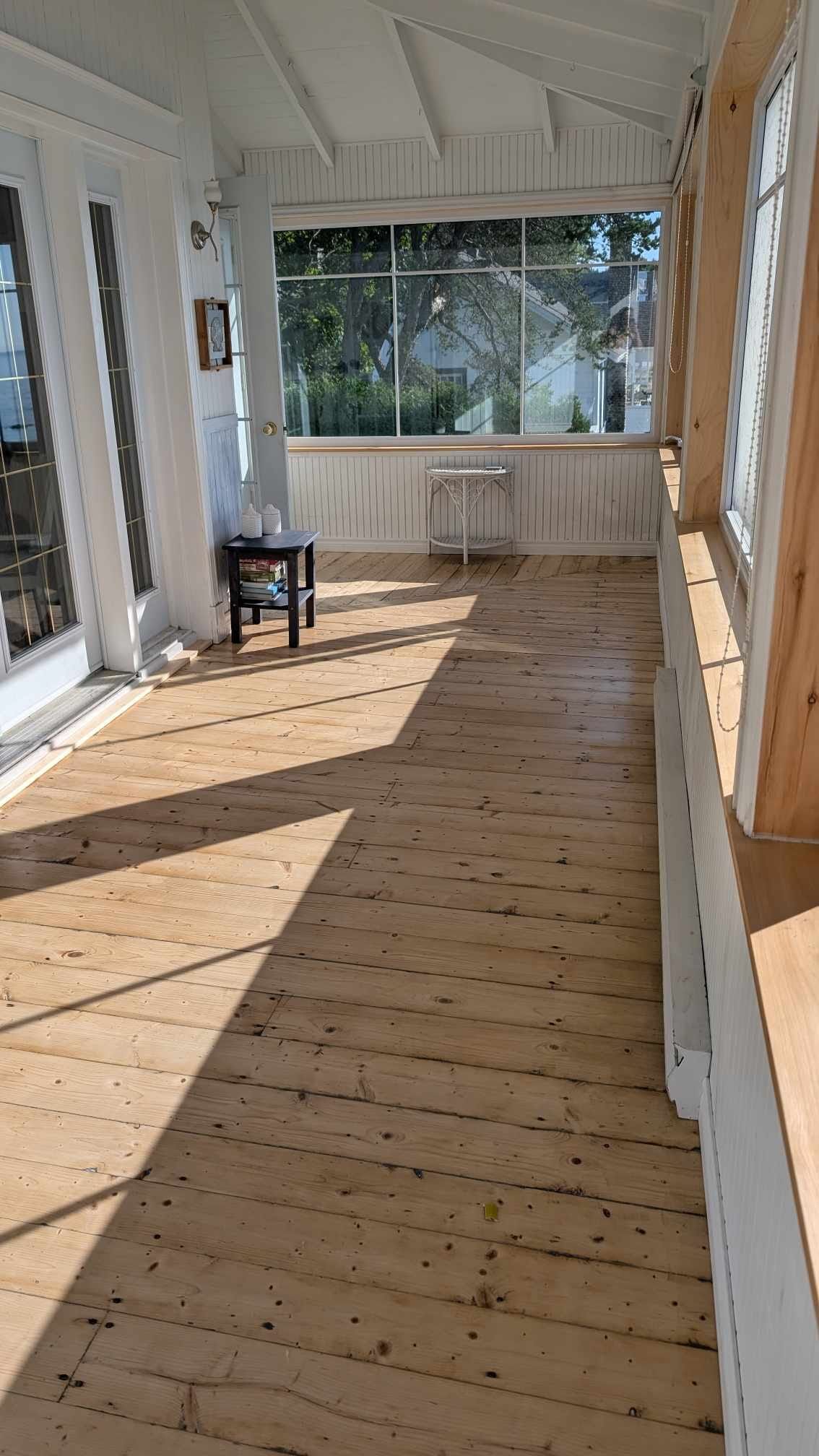 Un long porche en bois avec une chaise et une table.