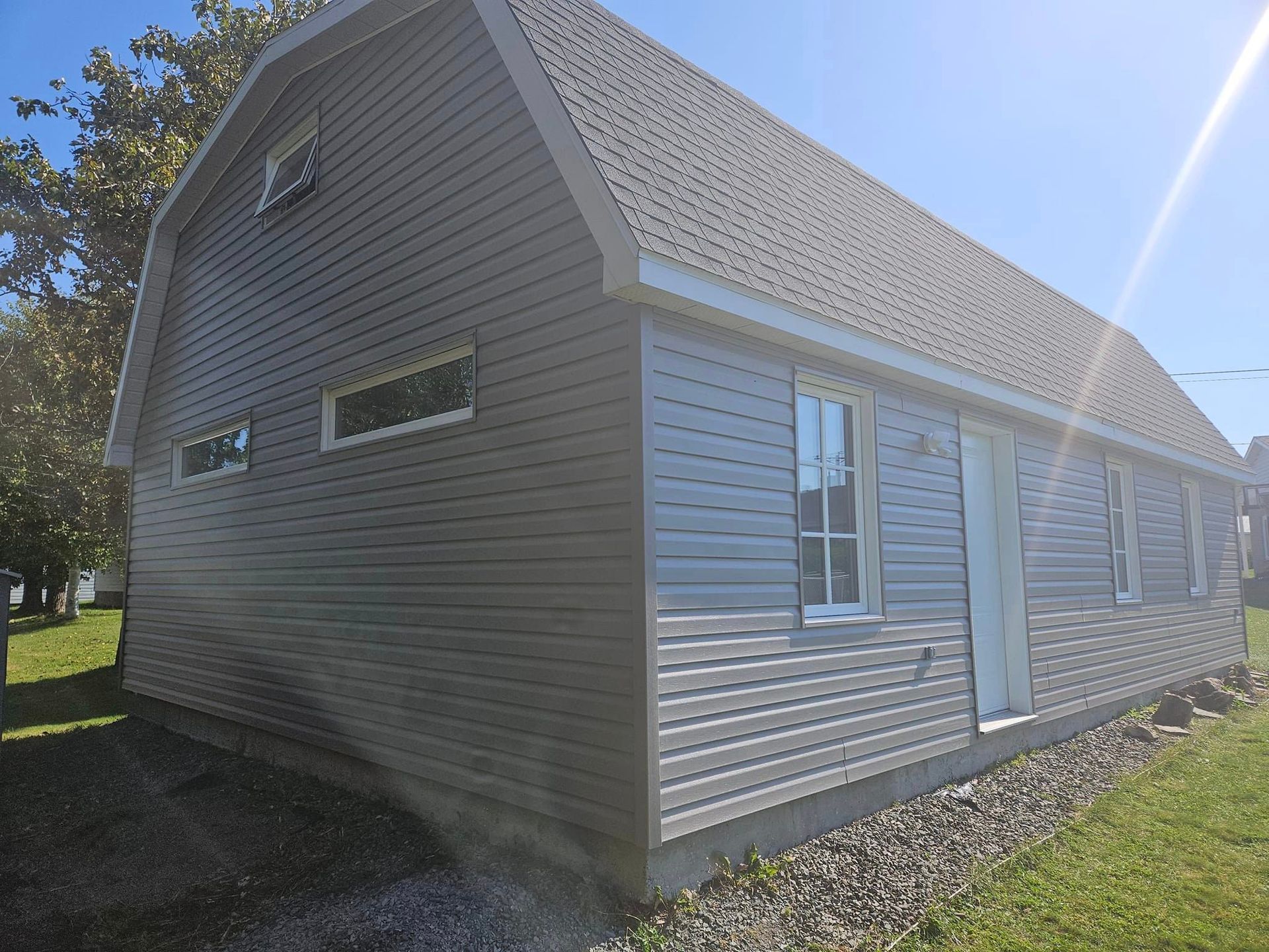 Une petite maison avec un revêtement blanc et une porte blanche