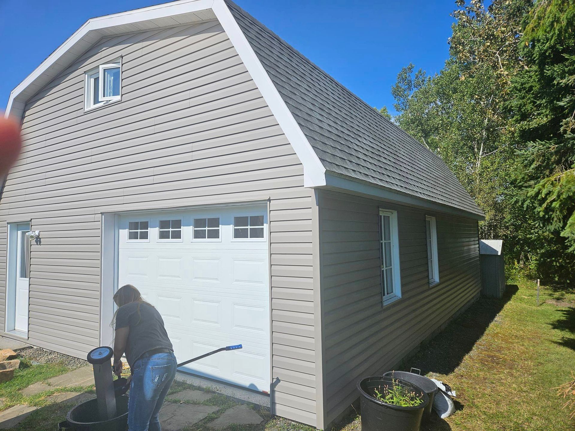 Un homme se tient devant un garage avec une porte blanche