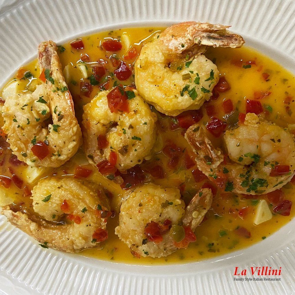 A white plate topped with shrimp and sauce on a table.