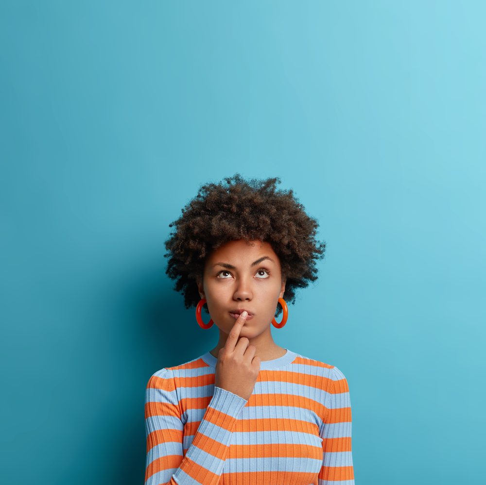 A woman in a striped shirt is holding her finger to her chin.