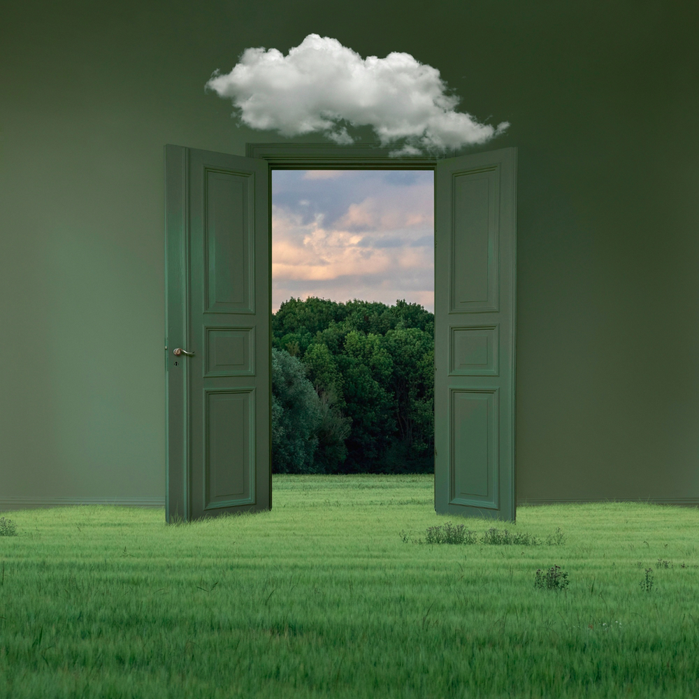 An open door leading to a field with a cloud above it