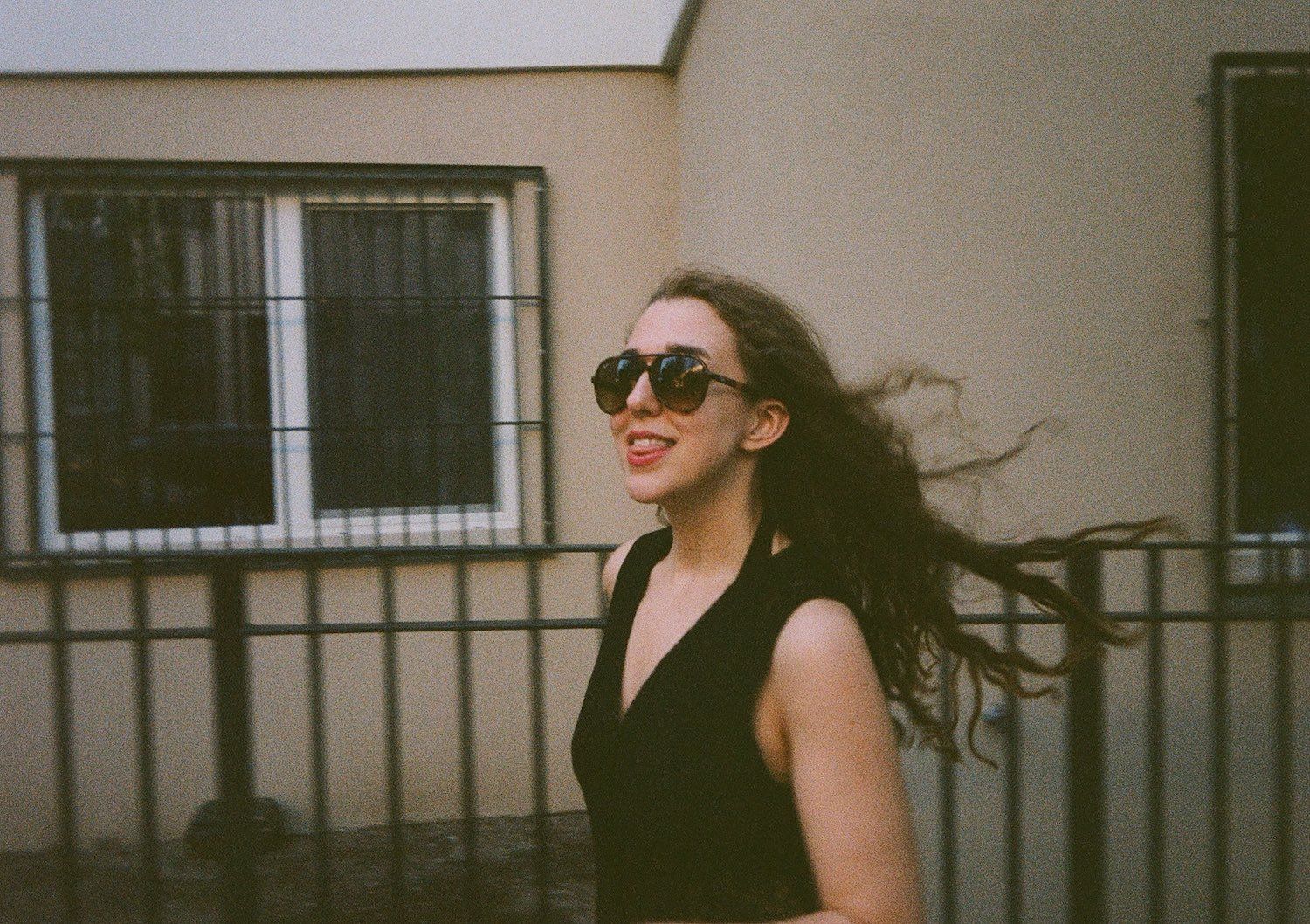 A woman wearing sunglasses is walking in front of a building.