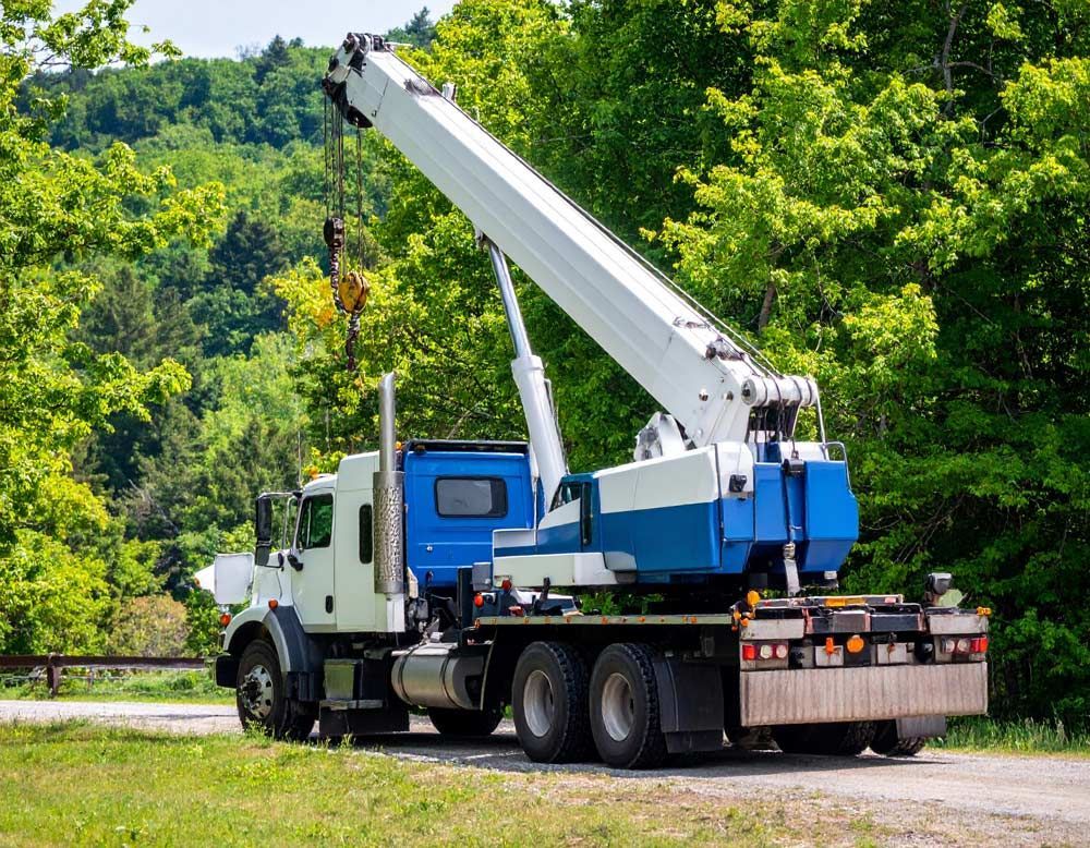 A truck with a crane attached to the back is parked on the side of the road.