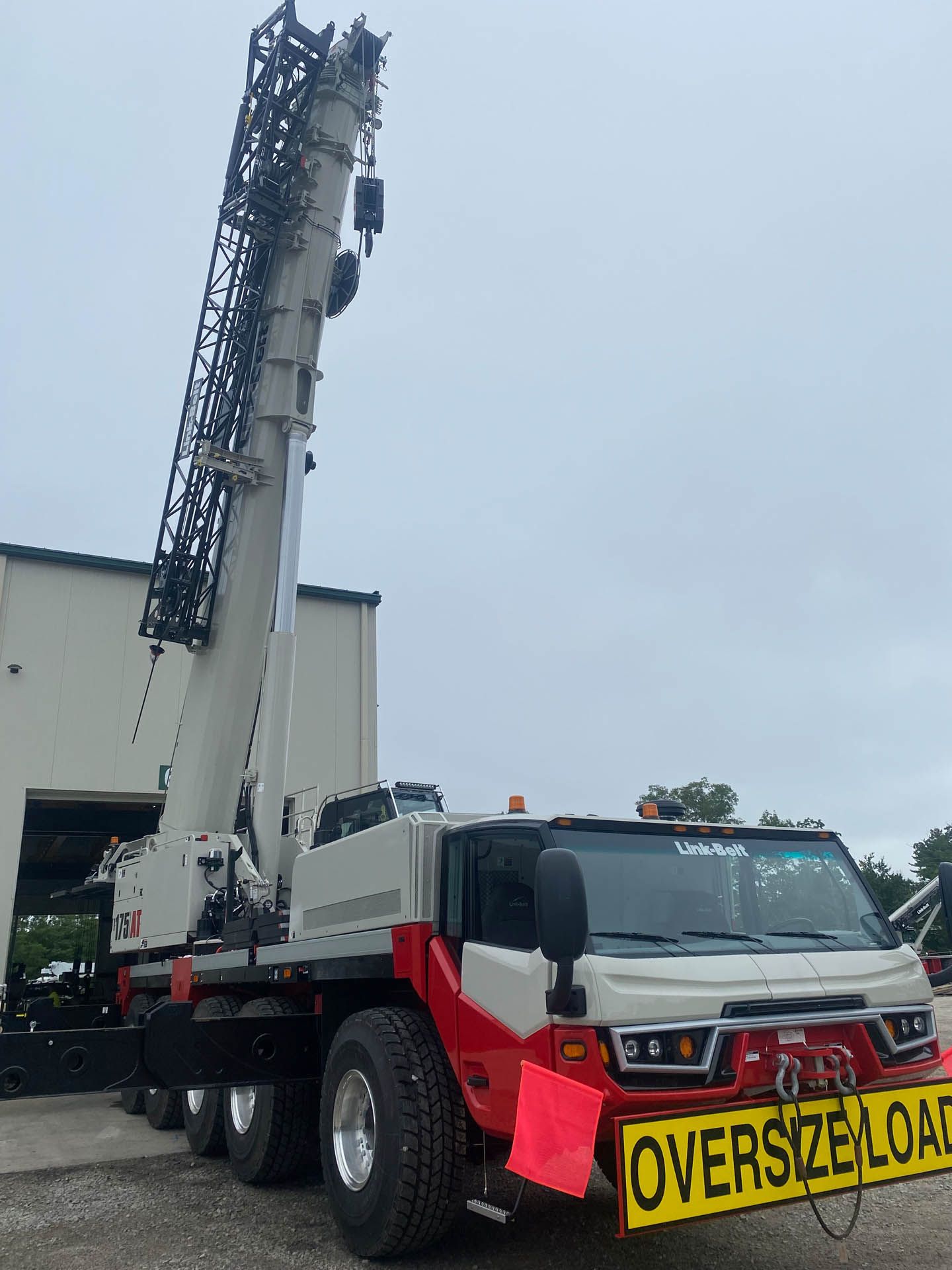 Two construction workers are standing in front of a crane at sunset.