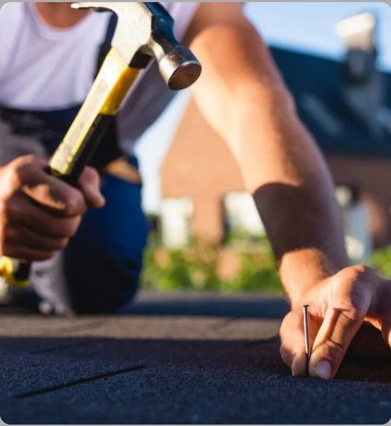 A man is working on a roof with a hammer and nails