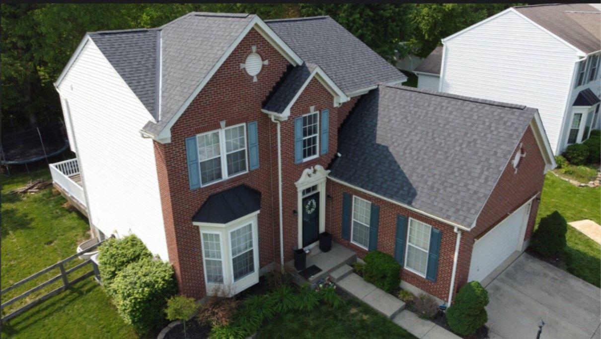 An aerial view of a large brick house with a new roof.