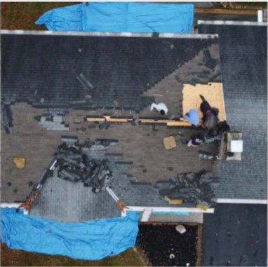 An aerial view of a roof with a blue tarp covering it