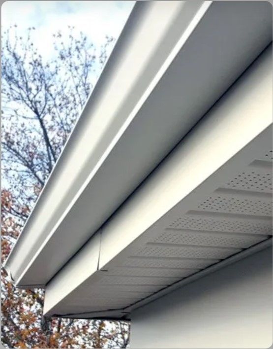 A white gutter on a house with trees in the background